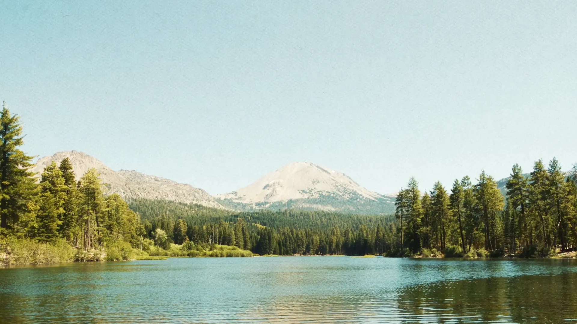 Mountain lake reflecting evergreen shoreline at dawn